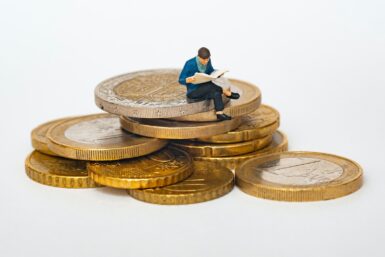 un homme travaille, assis sur sur une pile de pièces de monnaie