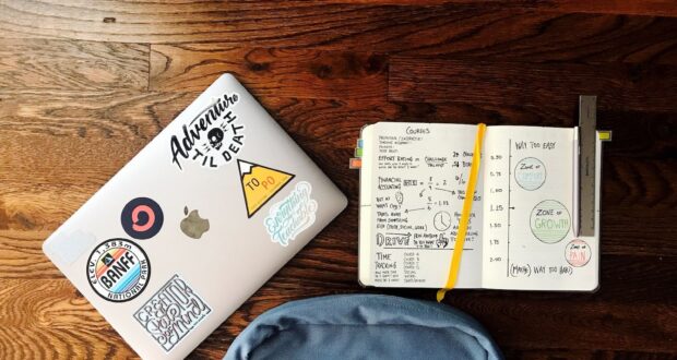 flat lay photography of blue backpack beside book and silver MacBook