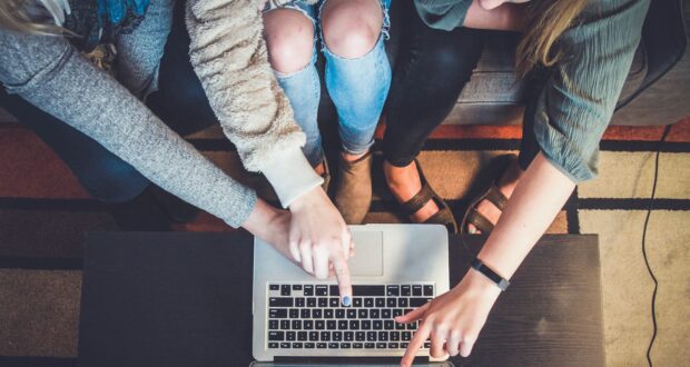 three person pointing the silver laptop computer