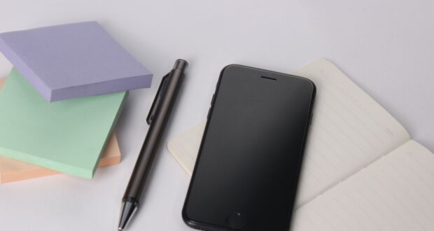 black iphone 4 beside black click pen