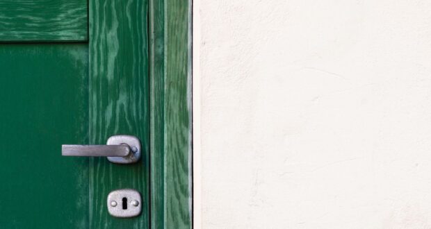 green wooden door beside white wall