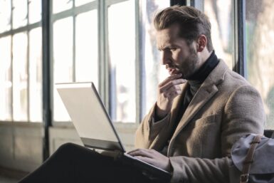 man holding his chin facing laptop computer