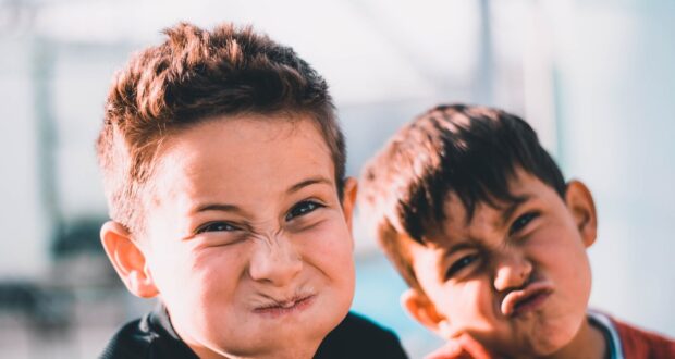 shallow focus photography of two boys doing wacky faces