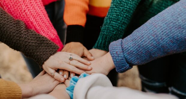 person in red sweater holding babys hand