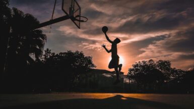 silhouette of boy jumping shooting ball