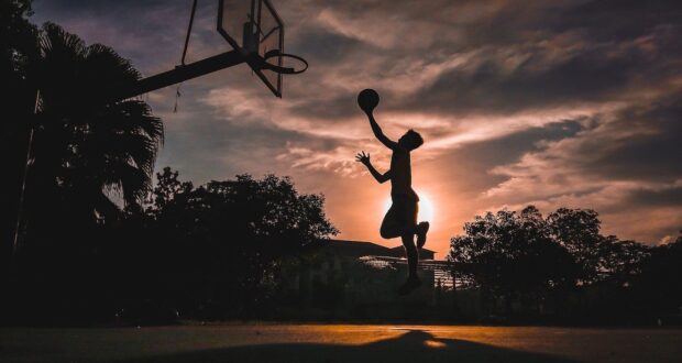 silhouette of boy jumping shooting ball