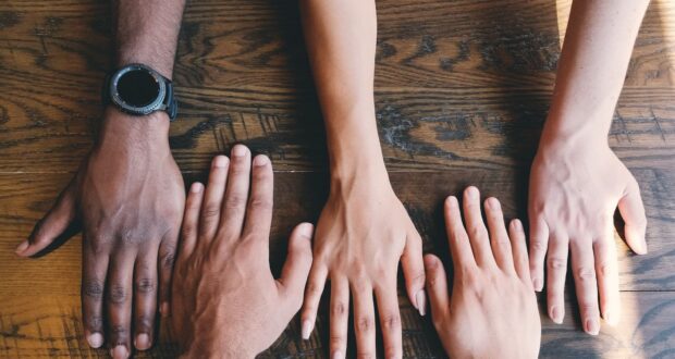 five human hands on brown surface